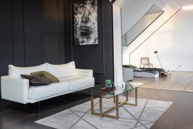 Lüks dairenin, beyaz şık yatak odası ve karanlık oturma odası olan minimalist, şık bir tasarımı var. Gündüz boyunca insansız ve güneş ışınları olmayan modern daireler.