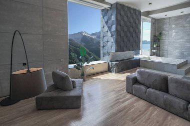 Süslü minimalist dizginlenmiş modern apartman dairesi, yüzme havuzlu geniş bir oda, dağlara bakan geniş panoramik pencereler. Gündüzleri insanlar olmadan