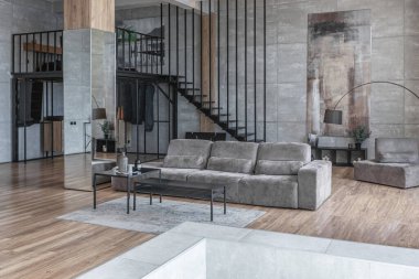 İki katlı bir dairenin modern iç dekorasyonunda gündüz vakti gri tonlarda tavan arası tarzı insanlar yok..