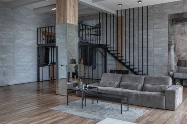İki katlı bir dairenin modern iç dekorasyonunda gündüz vakti gri tonlarda tavan arası tarzı insanlar yok..