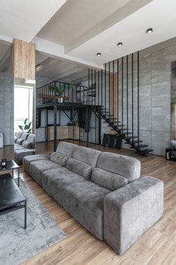 İki katlı bir dairenin modern iç dekorasyonunda gündüz vakti gri tonlarda tavan arası tarzı insanlar yok..
