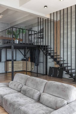 İki katlı bir dairenin modern iç dekorasyonunda gündüz vakti gri tonlarda tavan arası tarzı insanlar yok..
