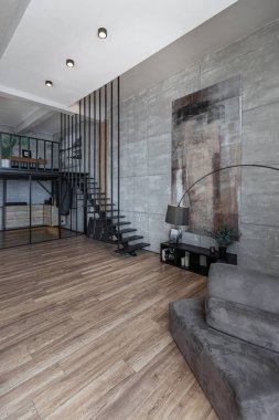 İki katlı bir dairenin modern iç dekorasyonunda gündüz vakti gri tonlarda tavan arası tarzı insanlar yok..