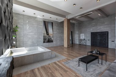Süslü minimalist dizginlenmiş modern apartman dairesi, yüzme havuzlu geniş bir oda, dağlara bakan geniş panoramik pencereler. Gündüzleri insanlar olmadan