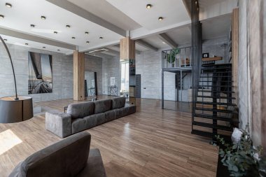İki katlı bir dairenin modern iç dekorasyonunda gündüz vakti gri tonlarda tavan arası tarzı insanlar yok..