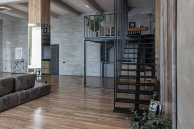 İki katlı bir dairenin modern iç dekorasyonunda gündüz vakti gri tonlarda tavan arası tarzı insanlar yok..