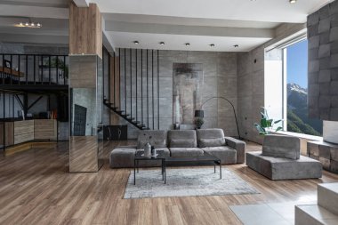 İki katlı bir dairenin modern iç dekorasyonunda gündüz vakti gri tonlarda tavan arası tarzı insanlar yok..