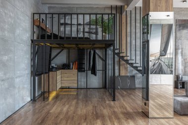 İki katlı bir dairenin modern iç dekorasyonunda gündüz vakti gri tonlarda tavan arası tarzı insanlar yok..