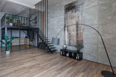 İki katlı bir dairenin modern iç dekorasyonunda gündüz vakti gri tonlarda tavan arası tarzı insanlar yok..