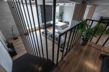 İki katlı bir dairenin modern iç dekorasyonunda gündüz vakti gri tonlarda tavan arası tarzı insanlar yok..