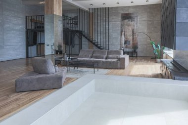İki katlı bir dairenin modern iç dekorasyonunda gündüz vakti gri tonlarda tavan arası tarzı insanlar yok..