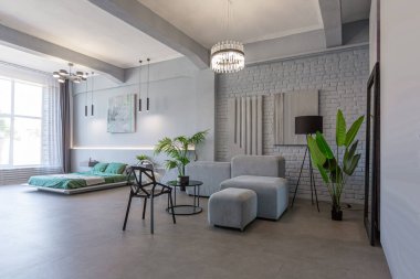 Modern bir stüdyoda, yeşil bitkilerle beyaz-gri renkli şık bir iç mekan. Gün ışığı ve içeride kimse yok.