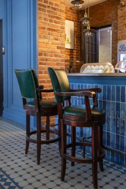 Mavi duvarları, ahşap döşemeleri ve tuğlaları olan kafe restoranının samimi, klasik bir iç mekanı. Mavi ve kırmızı sandalyeler masaların etrafına dizilmiştir. Doğal ışıklandırma ve lambalar.