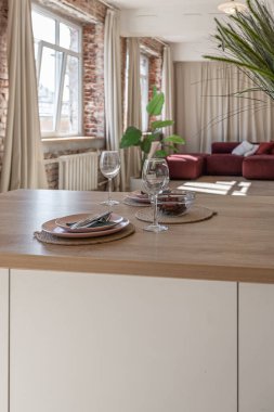 Modern mobilyaların ve doğal ışığın yumuşak sıcak renklerde şık bir dairede bulunduğu parlak ve ferah bir yaşam alanı.