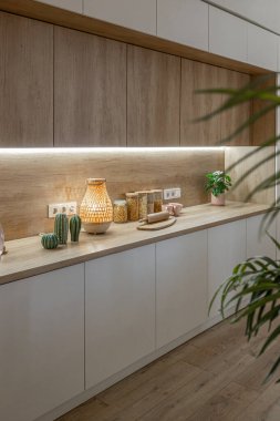 Modern mobilyaların ve doğal ışığın yumuşak sıcak renklerde şık bir dairede bulunduğu parlak ve ferah bir yaşam alanı.