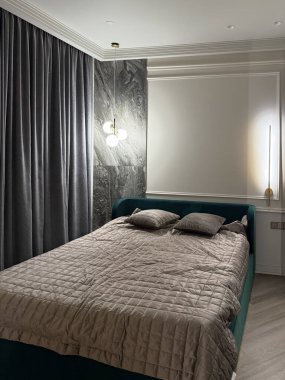 Bu rahat yatak odası yumuşak yastıklarla bezenmiş, içeriden aydınlatılmış, odanın atmosferini ve zarafetini artıran, zarif ve modern bir dolap ile tamamlanmış lüks bir yatak odası içeriyor..