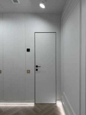 Parlak koridorda parlak kapılar ve ince dekoratif duvar elementleri var. Döşeme doğal ahşap tonlarını birleştirirken, yumuşak ışıklandırma sıcak bir ortam yaratıyor..