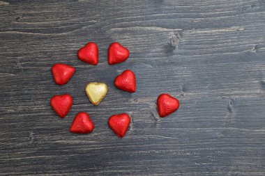 Kalp şeklindeki çikolatalar kırmızı ve altın folyolar ahşap arka planda fotokopi alanı ile birlikte. Sevgililer günün kutlu olsun.