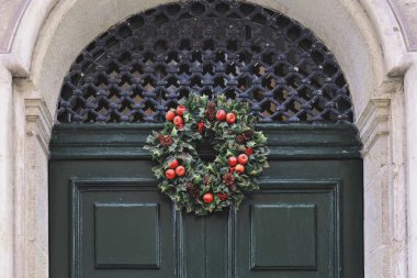 Evin giriş kapısında geleneksel yeşil ve kırmızı Noel çelengi asılı. Noel boyunca ön cephe dekoru inşa ediliyor