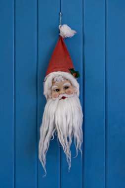 Beyaz sakallı, kırmızı şapkalı, parlak mavi tahta kapılı sevimli Noel Baba suratı. Etkinlik sırasında İskandinav Noel süsleri