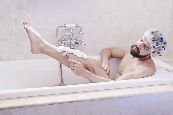 在米色复古浴室 戴淋浴帽的留胡子男人在洗澡时间会放松一下 刮胡子 皮肤和自我护理的概念 男人的健康是问题 图库照片