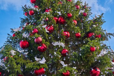 Noel ağacı süsleri, beyaz güvercin heykelcikleri ve parlak ışıklarla süslenmiş.