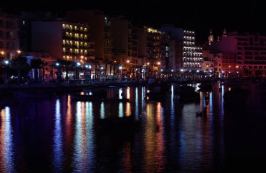 Rıhtım güvertesi gece aydınlık binaların rengarenk yansımaları ve suyun üzerindeki ışıklarla
