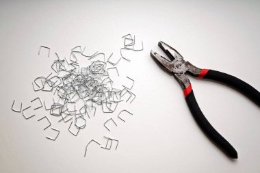 Pliers and Staples on White Surface in Minimalist Composition with Copy Space clipart