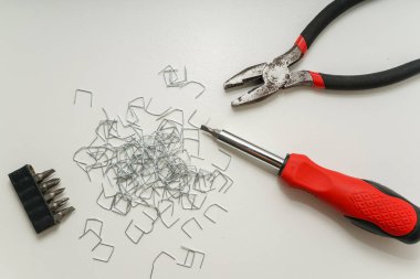 Minimalist Kompozisyonda Beyaz Yüzeyde Araçlar ve Staples, üst görünümde