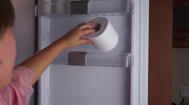 Genç bir kadının tuvalet kağıdını buzdolabının rafına koyması, nem ve koku kontrolü ile ilgili sosyal medya eğilimini ortaya çıkarıyor. Moda komedi çözümleri, ev temizliği eğlenceli bir deneye ilham verir.