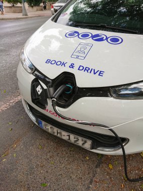 Halka açık kaldırıma bağlı kompakt elektrikli araba, düzenli olarak şehir rutini için şarj ediliyor, temiz enerji erişimi için köprü şarj ediliyor, emisyonları azaltmak için ileri görüşlü hareketlilik sinyalleri veriyor