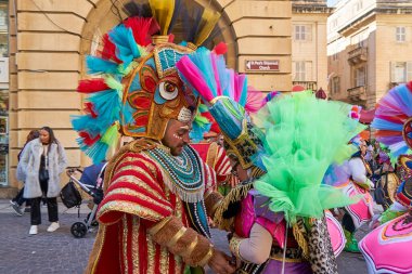 Maskeli oyuncular, Malta güneşi altında cesur giysiler içinde parıldıyor, durdurulamaz karnaval ruhu tarihi şehri dokuyor: Valletta, Malta - 19.02.2023