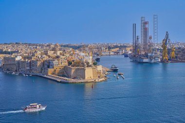 Yukarı Barrakka 'dan La Guardiola kalesinin panoramik manzarası açık yaz gökyüzü altında deniz rıhtımı ve turistik tekne: Valletta, Malta - 24 Ağustos 2019