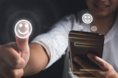 Değerlendirme ve tatmin kavramı. Gülümseyen adam, tanımlanamayan bir cep telefonu modeliyle mükemmel bir eleştiri gösterdi. Siyah arkaplanda orta ölçekli yakın çekim.
