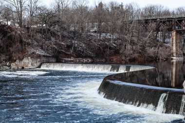 Kışın başında Paris 'te bir baraj. Paris, Ontario, Kanada 'da şelale şelalesi. Kanada 'nın Paris şehrinde soğuk ve bulutlu bir günde beyaz su akıntısı.