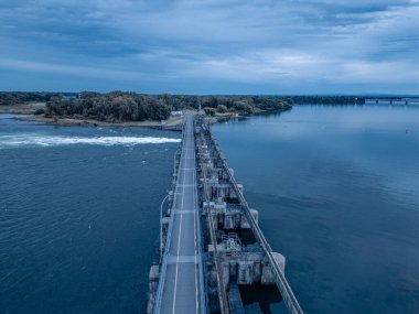 Bir su kütlesini geçen bir köprünün hava perspektifi, Salabery de Valleyfield 'da bulutlu bir gökyüzünün altında gölü ve engin ufku olan manzaralı bir doğal manzara sergiliyor.