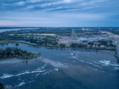 Bir su kütlesini geçen bir köprünün hava perspektifi, Salabery de Valleyfield 'da bulutlu bir gökyüzünün altında gölü ve engin ufku olan manzaralı bir doğal manzara sergiliyor.