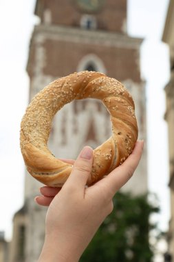 Krakow Meydanı Rynek Parlak Polonya 'da elinde simit ve geleneksel Polonya mutfağı atıştırmalığı tutan turist kadın.