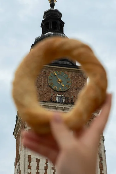 Krakow Meydanı Rynek Parlak Polonya 'da elinde simit ve geleneksel Polonya mutfağı atıştırmalığı tutan turist kadın.
