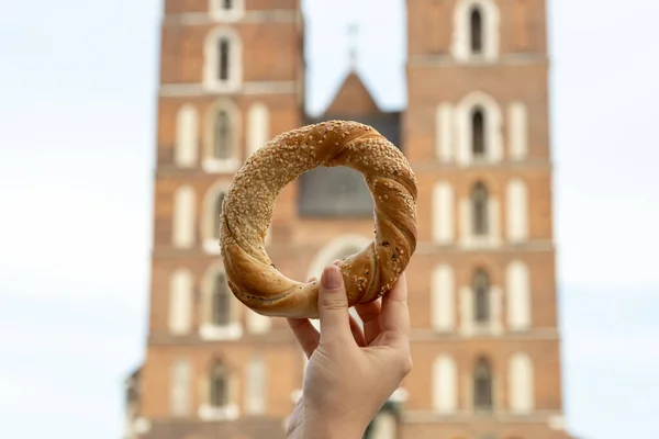 Krakow Meydanı 'ndaki St. Mary Bazilikası' nda elinde simit ve geleneksel Polonya mutfağı atıştırmalığı tutan turist kadın Rynek Glowny Polonya