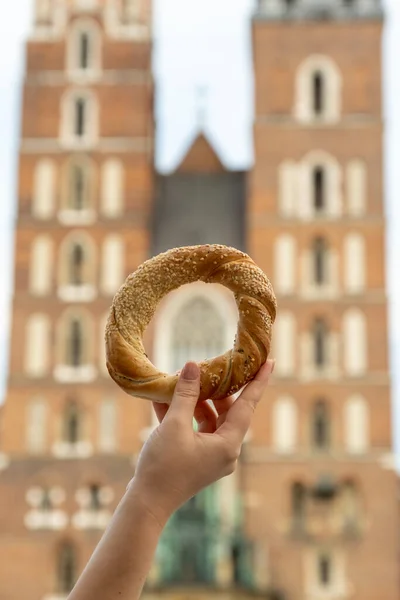 Krakow Meydanı 'ndaki St. Mary Bazilikası' nda elinde simit ve geleneksel Polonya mutfağı atıştırmalığı tutan turist kadın Rynek Glowny Polonya