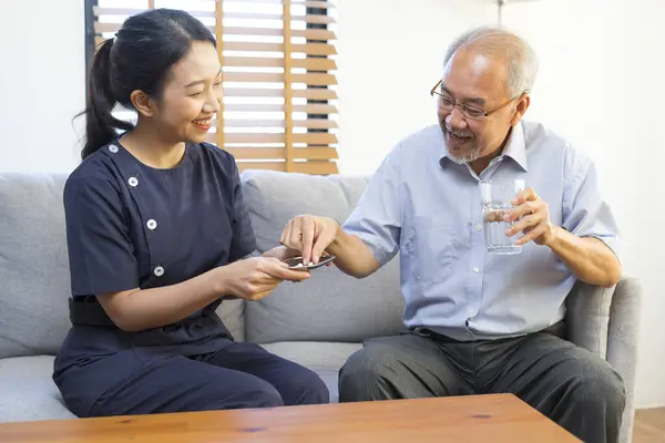 Smiling Nurse Giving Medicine Senior Asian Man Nursing Home Assisted Stock Image