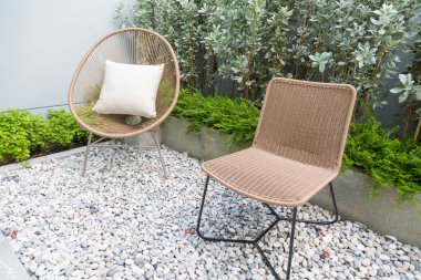 Bahçesinde çiçek açan çalılar ve kaya bahçesi olan bahçe sandalyeleri..