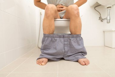 Asyalı adam klozette otururken ishal oluyor. Mide ağrısı, banyoda kabızlık..