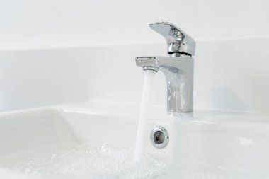 Banyoda akan suyu olan modern musluk, yakın çekim.