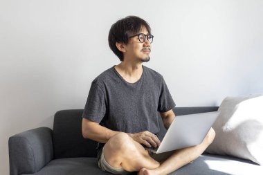 Evdeki koltukta dizüstü bilgisayar kullanan bir adam..