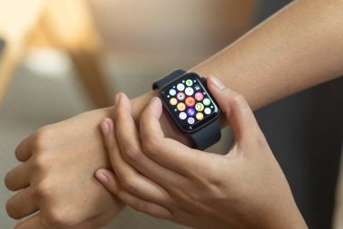 Kadın eli akıllı saati tutuyor.