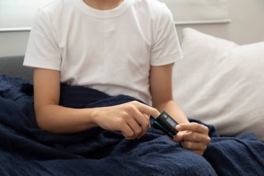 Çocuk evde battaniyenin içinde yatarken termometre kullanıyor.