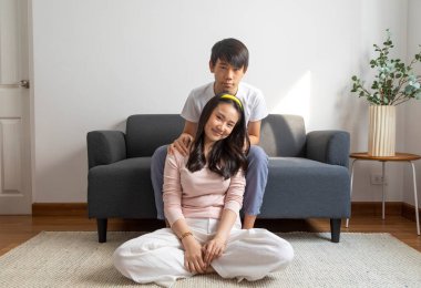 Asyalı bir aile kanepede oturuyor ve evde televizyon seyrediyor.