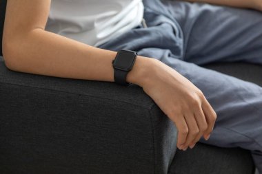 Evde akıllı saat kullanan genç bir kadın.